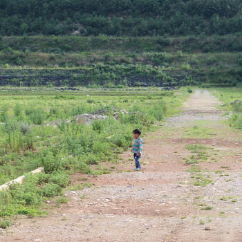A little boy surveys a field outside of Dali Old Town